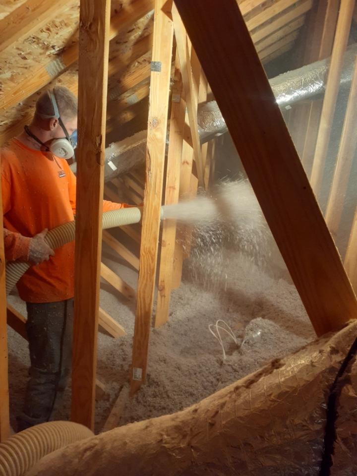 Employee spraying Cellulose insulation.